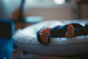 Baby laying on a bed with focus on the feet